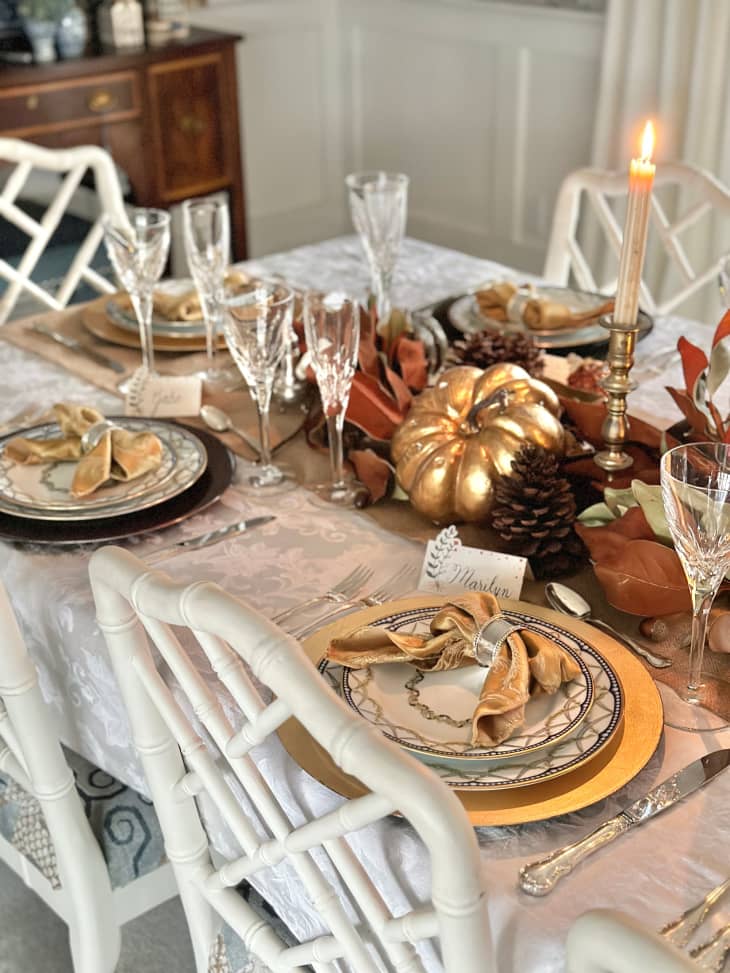 table setting for holiday party with golden pumpkins and candle sticks