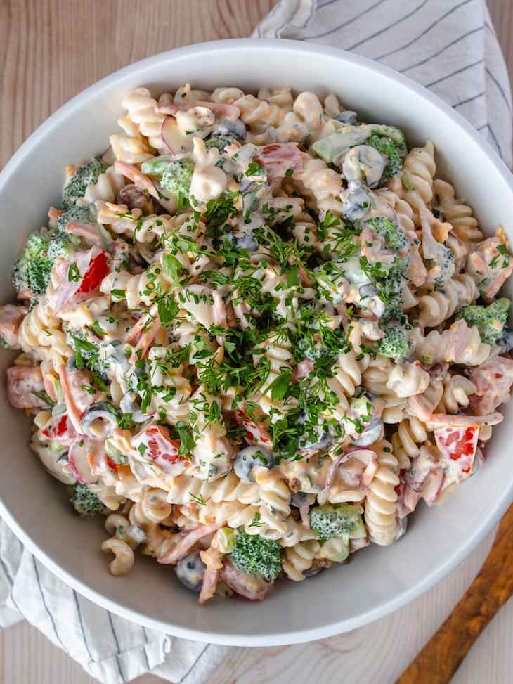 A photo of Ranch pasta salad with broccoli, red peppers and chopped parsley on top