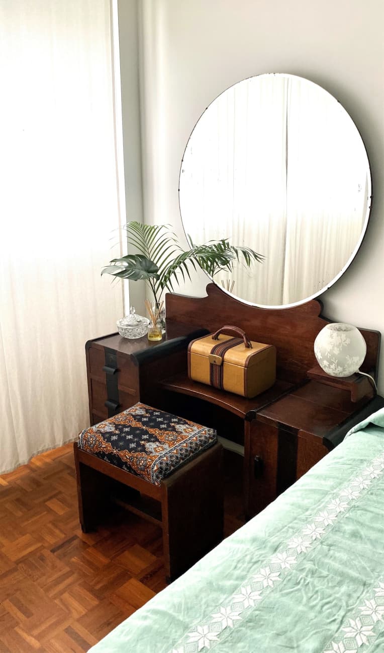 Vanity with circular mirror next to bed