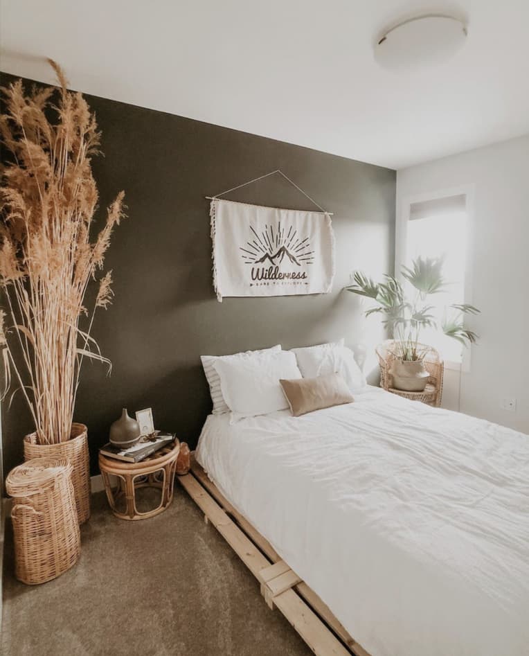 Wood pallet bed with white bedding against a deep green wall