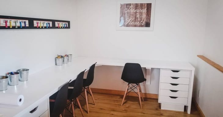 a homeschool room features a long L-shaped desk with four black chairs