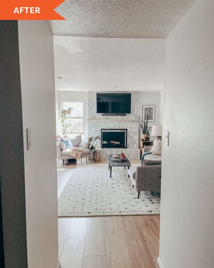 “After” photo of room that’s been completely redone and features a lot of DIY projects. Lot’s of white, tiled fireplace, gallery wall above sofa