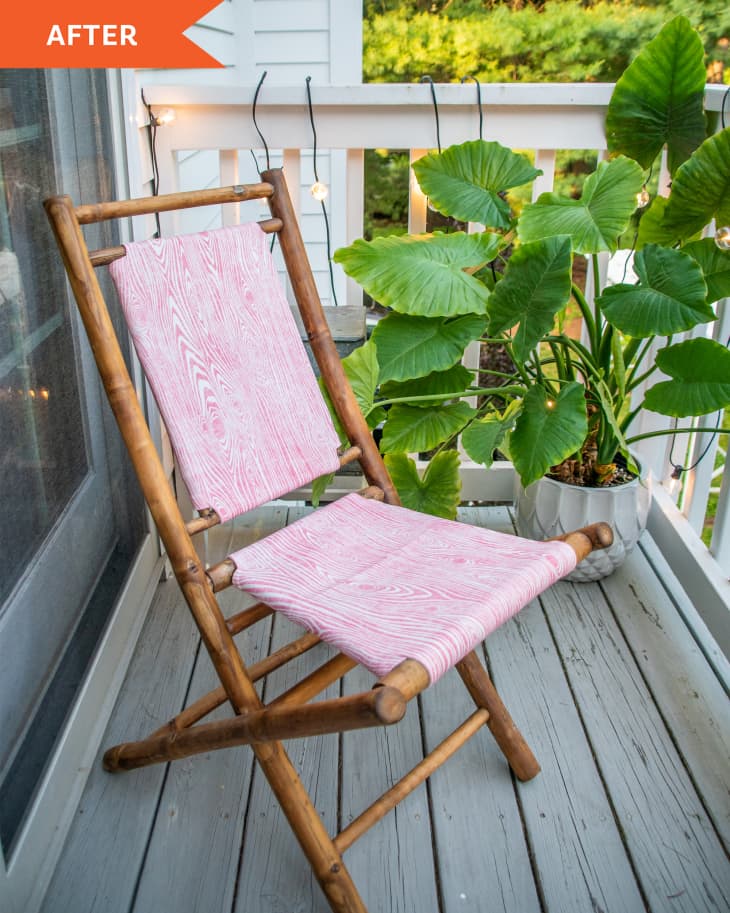 After photo of DIY outdoor chair. Fabric has a pink and white wood grain pattern on it. Chair is on patio with plants