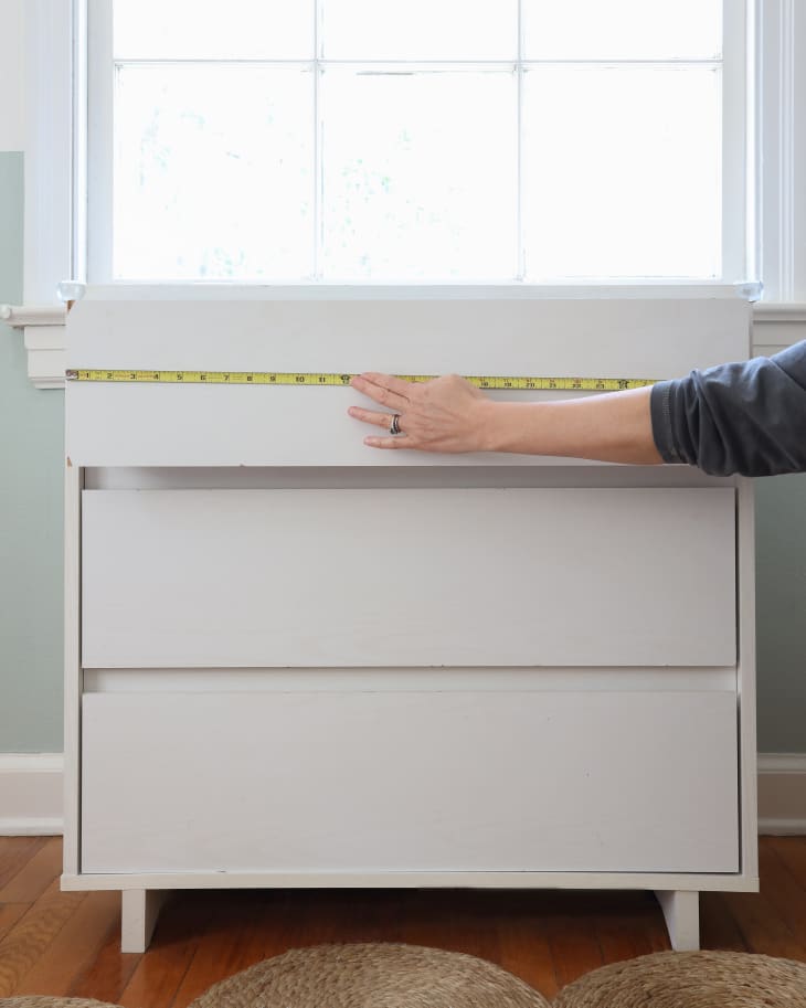 white dresser with hands holder a measuring tape