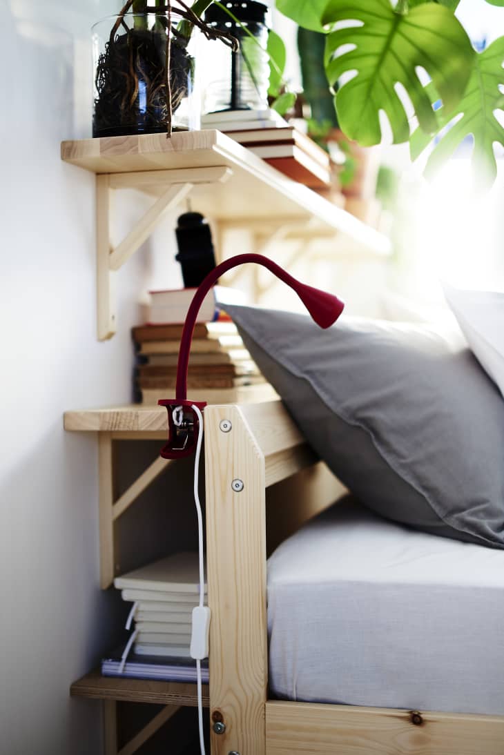 IKEA shelving installed behind a bed to serve as a nightstand