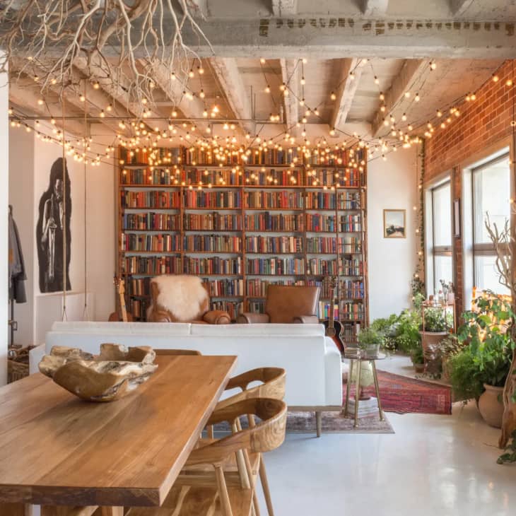 a loft apartment with a large floor-to-ceiling bookshelf on one wall