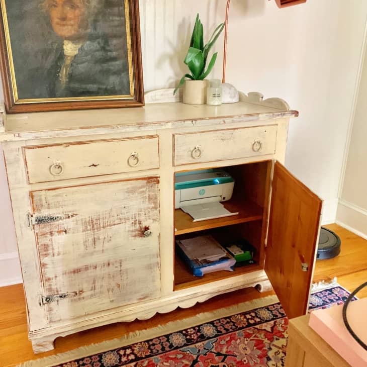 a printer hidden in the bottom shelf of a cabinet