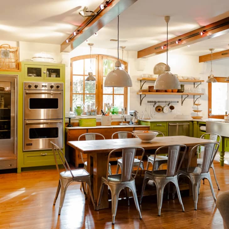an industrial kitchen with exposed beams and green cabinetry