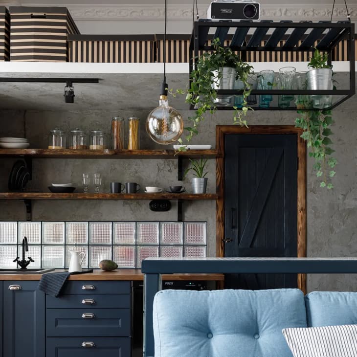 a studio apartment kitchen with exposed wood shelving and glass backsplash