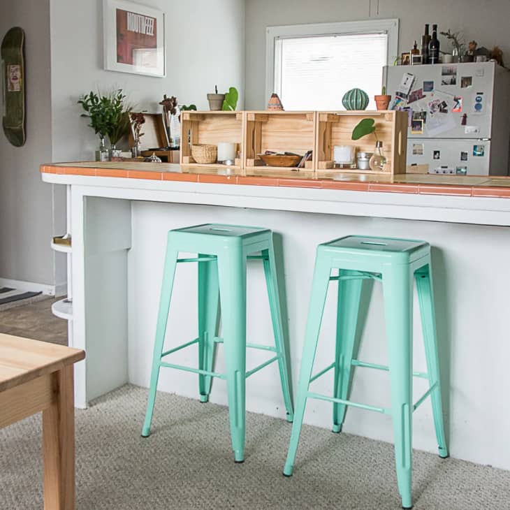 a gray kitchen with mint stools