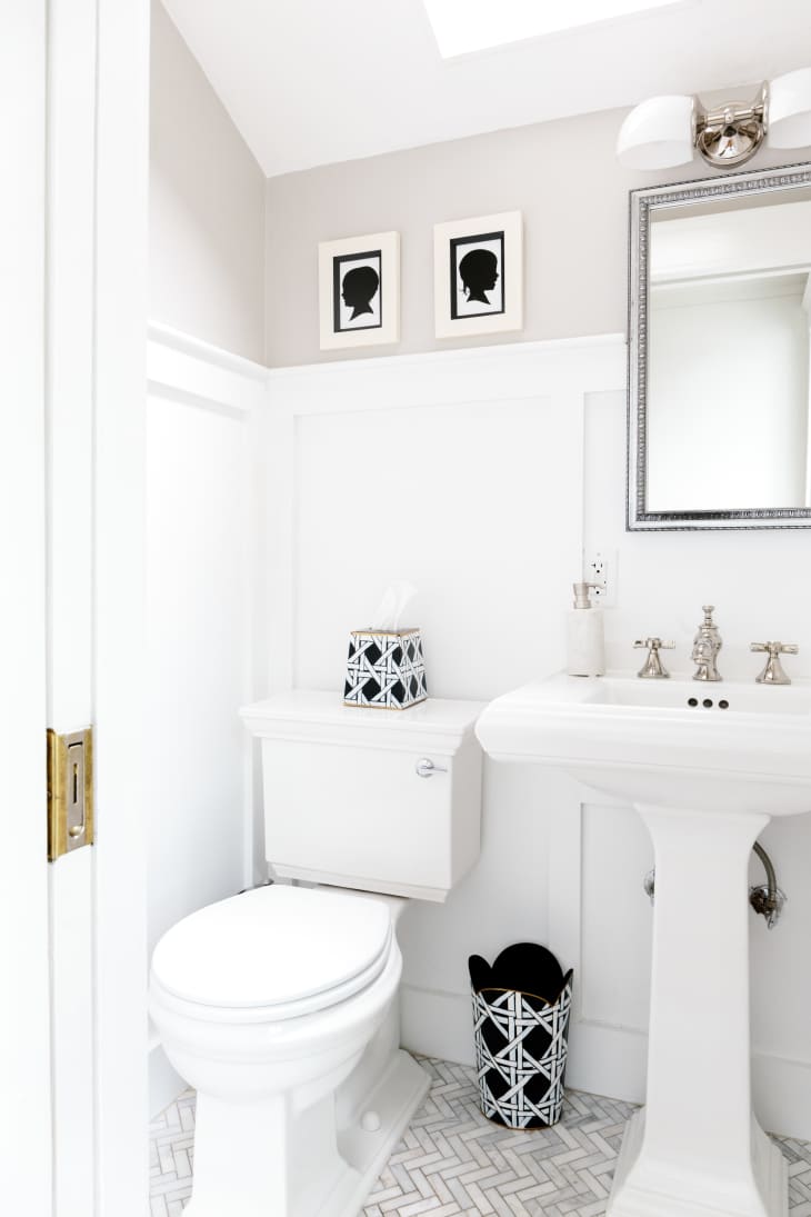 All white half bath with black and white art and accessories