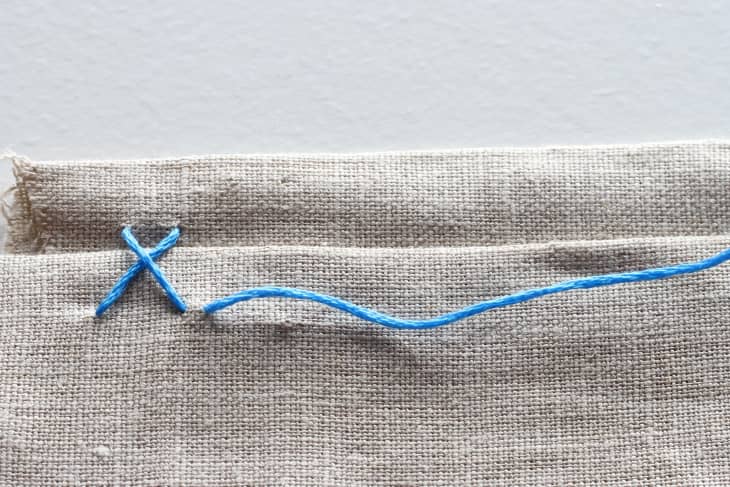 X stitching in canvas with blue thread.