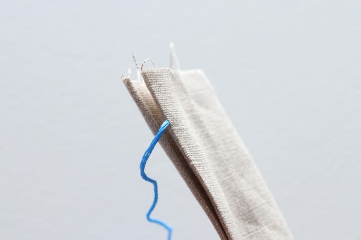 blue thread hanging out of canvas-like material