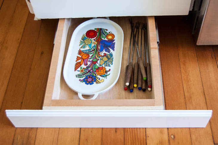 A ceramic serving platter is placed in a hidden drawer, where it is added to toe kick areas