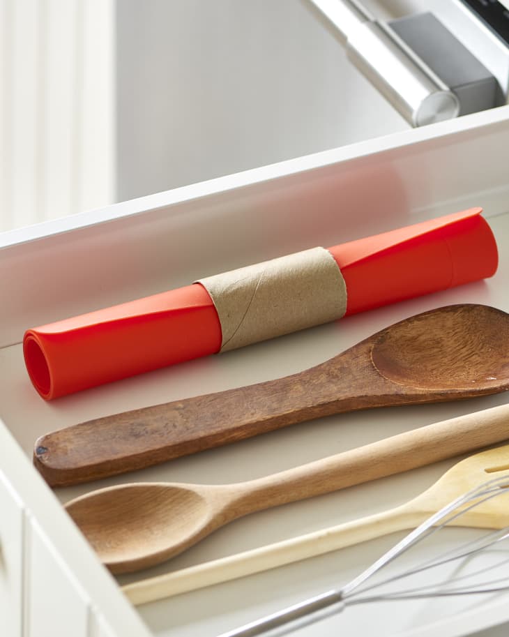 A toilet paper tube is used to keep a red baking mat tidy