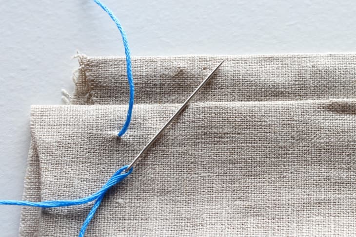 blue thread knotted in canvas material attached to needle