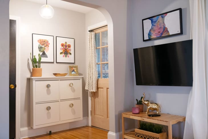A small entryway with a wall-mounted storage cabinet below framed artwork