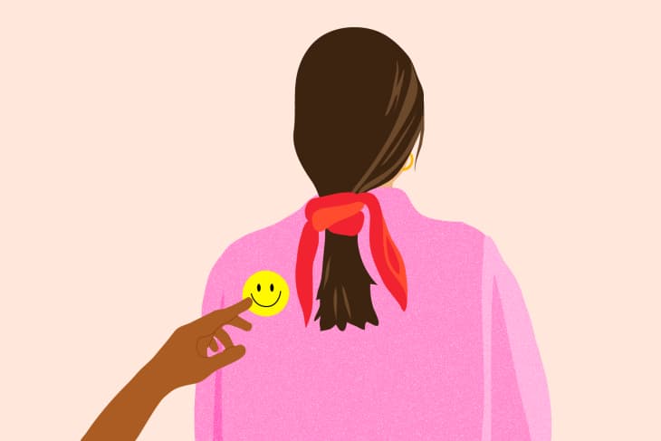 Clipart of a brown hand pointing to a yellow smiley face located on the left backside of a woman's pink shirt