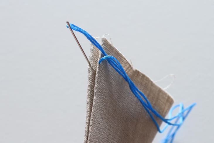 Needle going through canvas-like material with blue thread