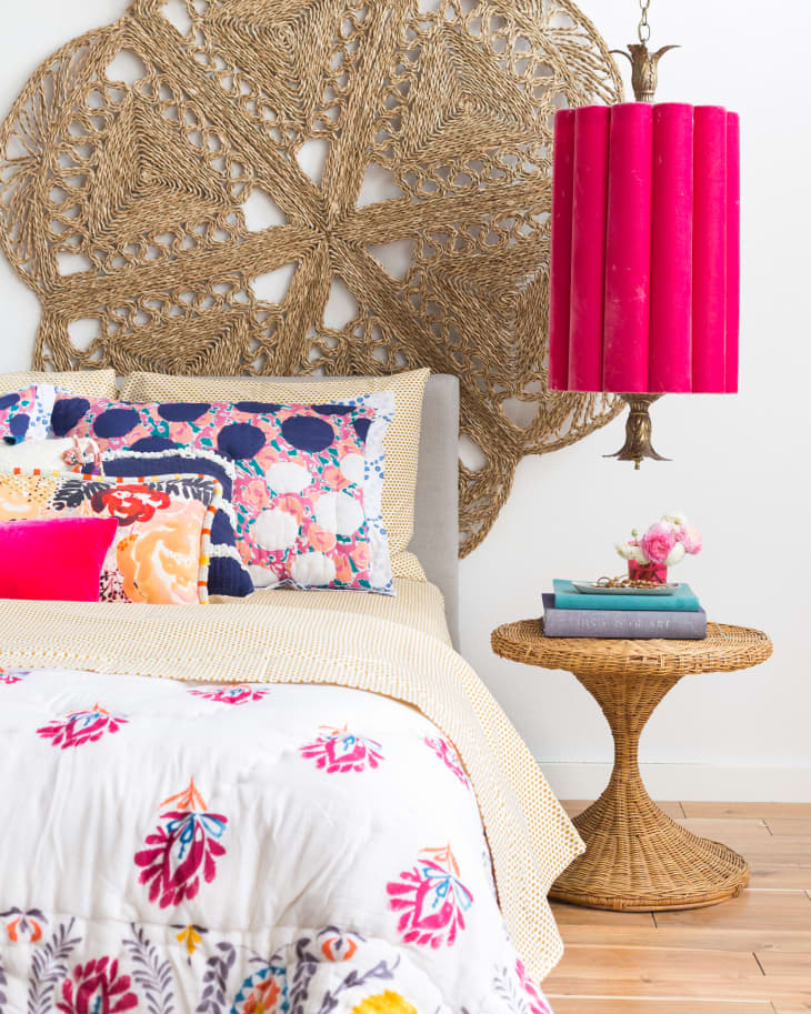a bohemian bedroom with a pink lampshade on the nightstand