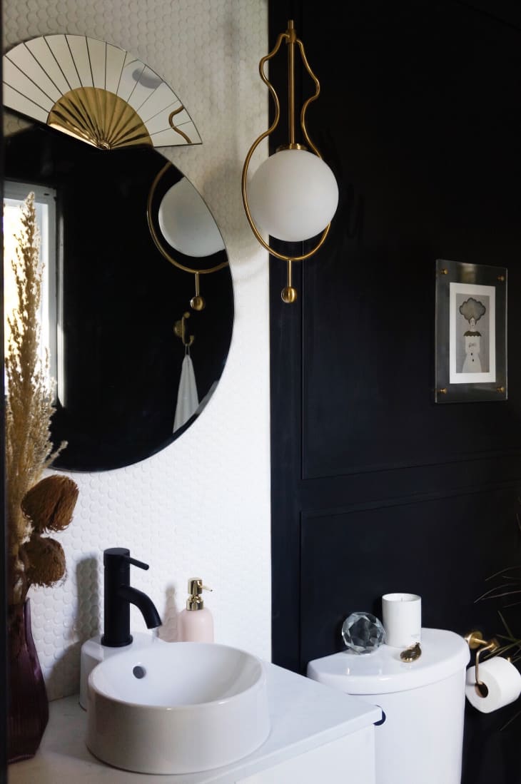 Gold art deco decor and black walls punch up this small bathroom.