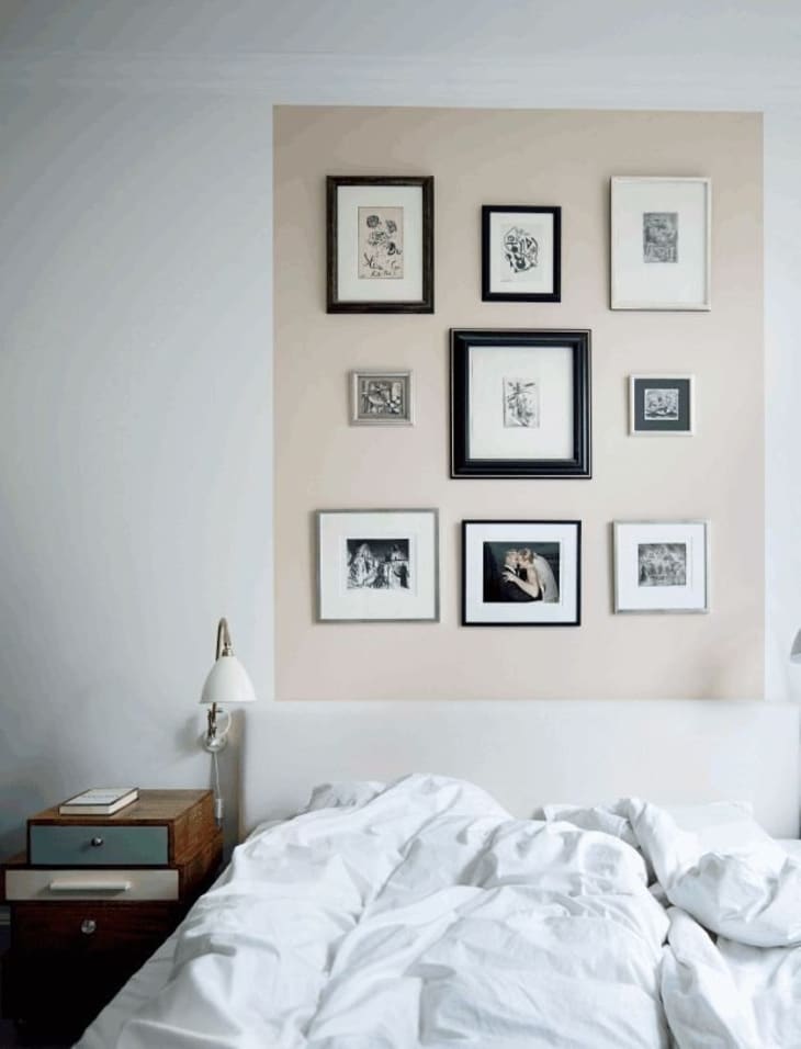 a beige rectangle, oriented vertically, serves as a headboard alternative and features several wall hangings as well