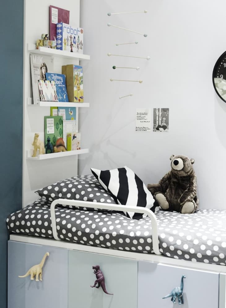 A kids' room with a platform bed on top of painted IKEA cabinets with dinosaur drawer pulls