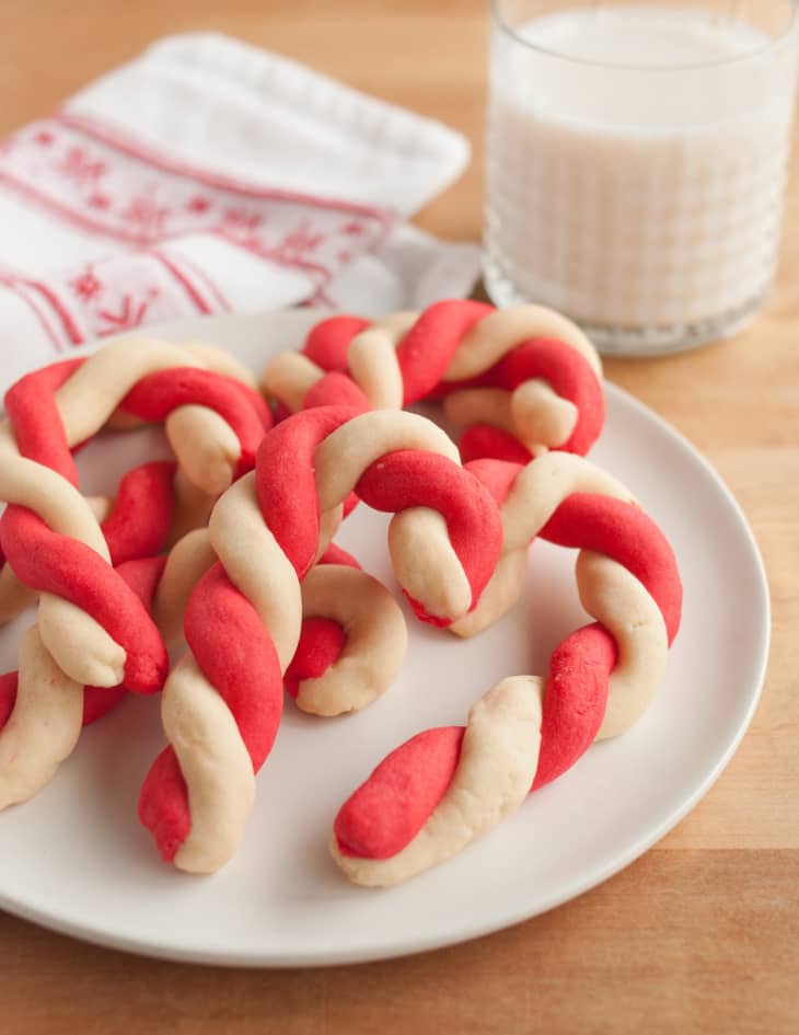 Candy cane cookies on a plate with a glass of milk in the background.