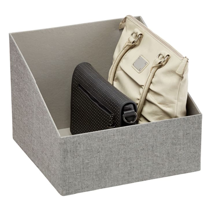 A woman's purse and a handbag is stored in a grey purse storage bin