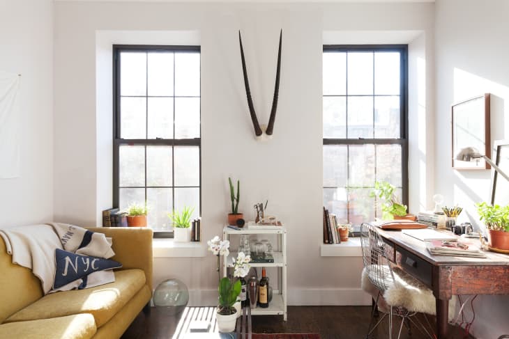 Living room with desk and sofa; windowsills are used as shelves