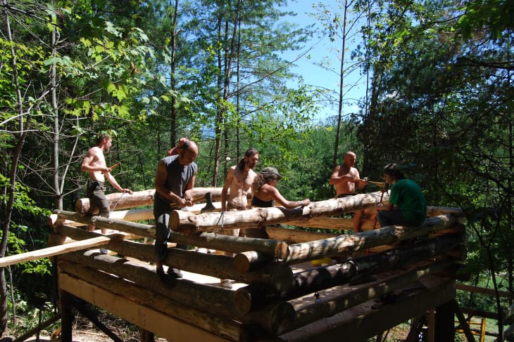 Group of people building cabin together in the woods