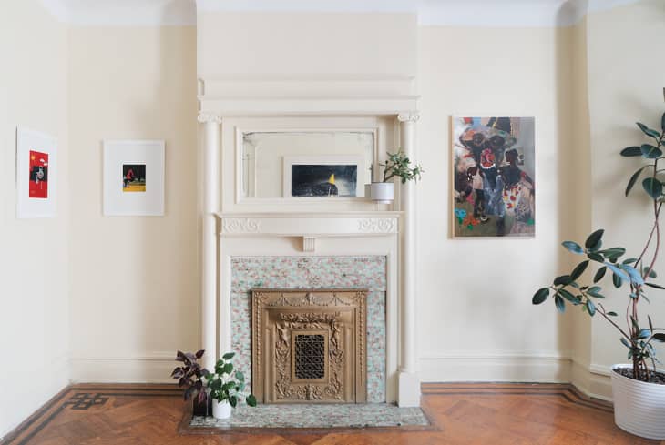 Installation by Stephanie Baptist. White room with antique fireplace, paintings on walls, plants