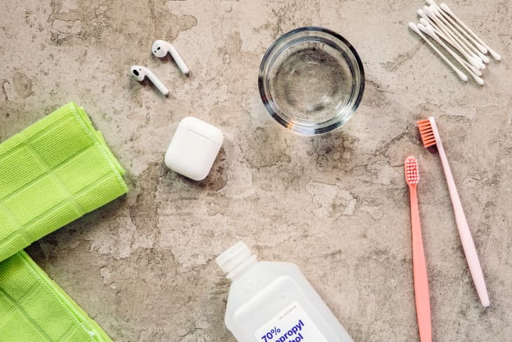 Apple airpods headphones along with cleaning materials, such as isopropyl alcohol, cotton swabs, toothbrushes, and a cloth