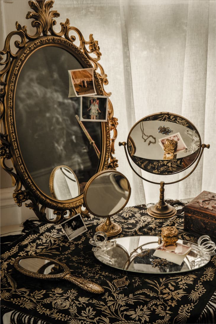Antique vanity with various mirrors, jewelry, and old photos