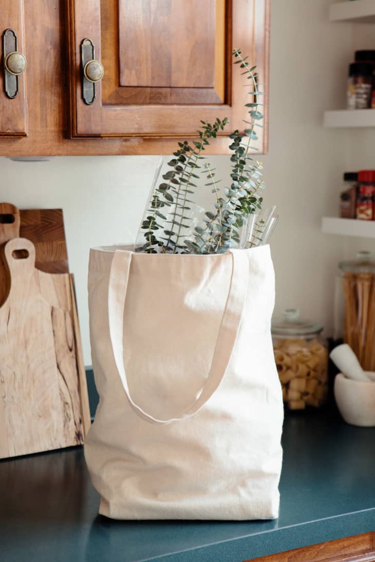 Bouquet of eucalyptus sticking out of grocery tote bag