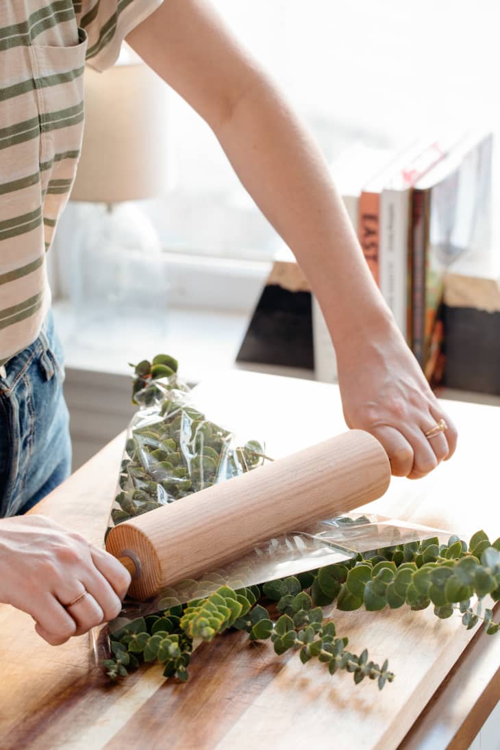Pressing down on eucalyptus with rolling pin