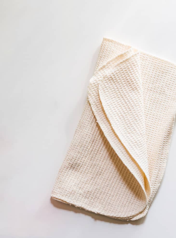 An unbleached cotton cleaning cloth folded on a white background