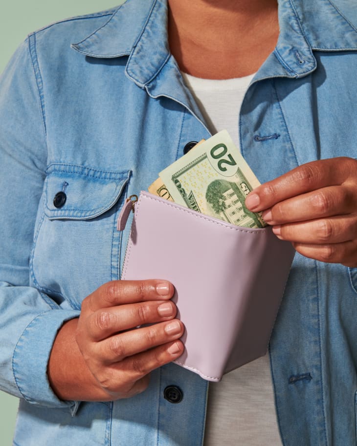 Closeup of woman taking a twenty dollar bill out of a purple wallet