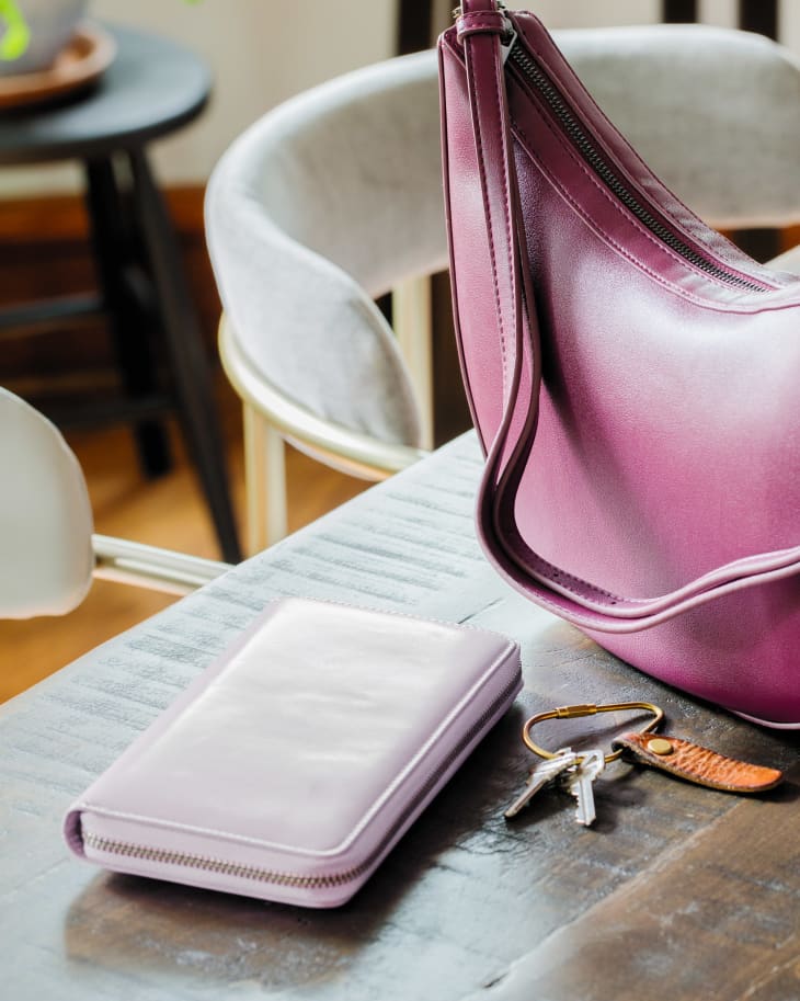 Purple purse, light purple wallet, keys on a dining room table