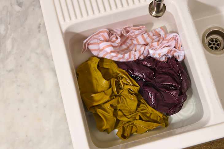 overhead shot of someone cleaning clothes in a kitchen sink
