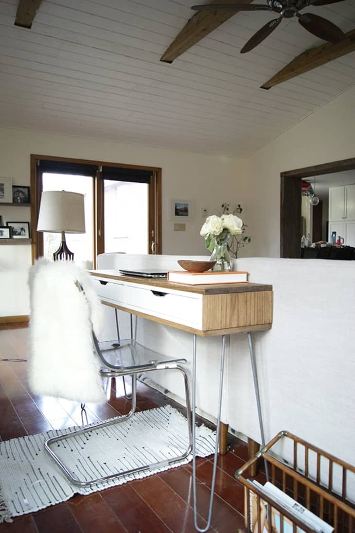 sleek white and wooden desk behind couch