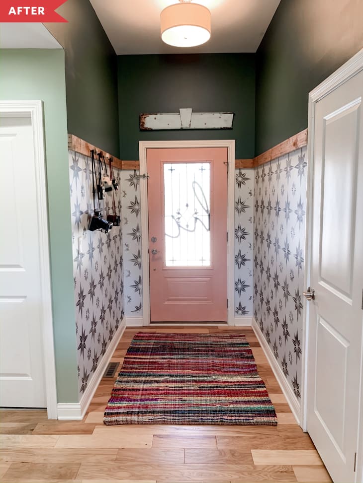 After: entry with black and white stenciling on the bottom of the walls, green on the top, and a pink door