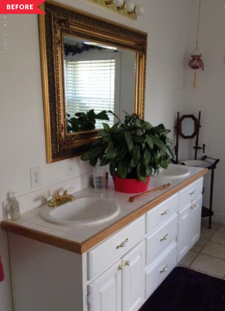 Before: White '90s-style bathroom vanity with wood trim and a brass mirror above