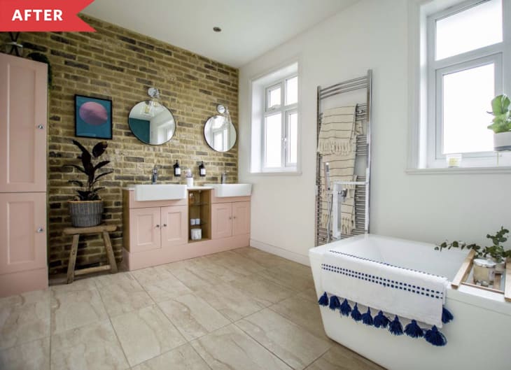 After: Large bathroom with exposed brick wall, standalone tub, and pink vanities