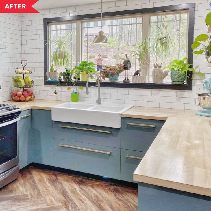 After: Kitchen with blue cabinets, herringbone wood floor, and large window