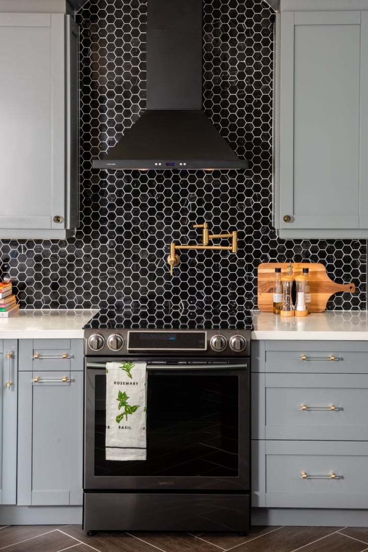 kitchen with black hex tile backsplash and gold pot filler over range