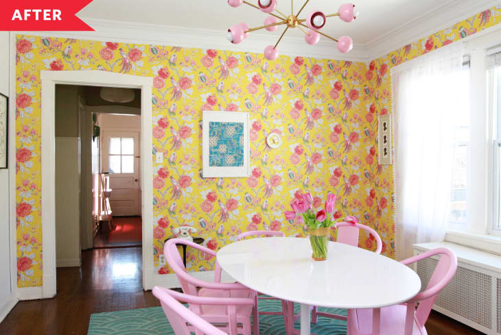 After: dining room with yellow floral wallpaper, white oval table, and pink chairs and pink light fixture