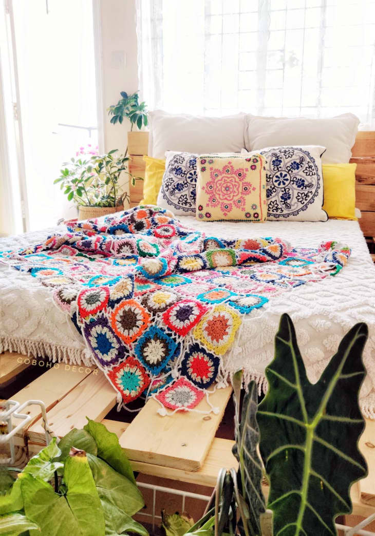 Pallet bed wtih colorful throw and patterned pillows