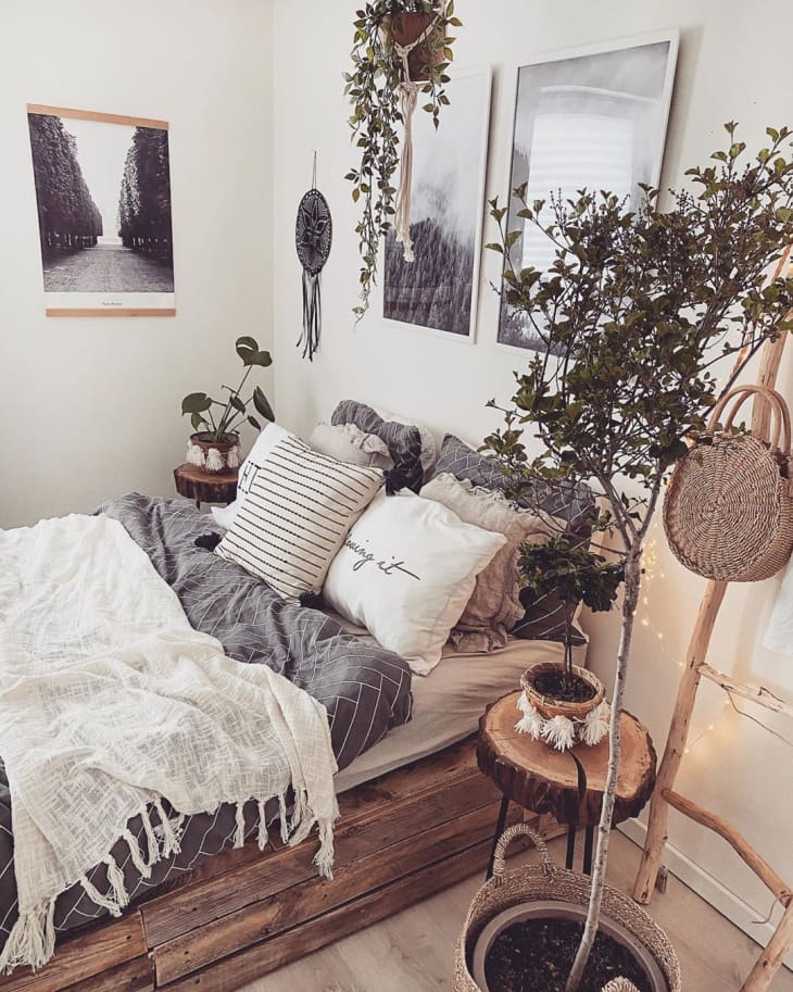 pallet bed surrounded with plants and black and white artwork