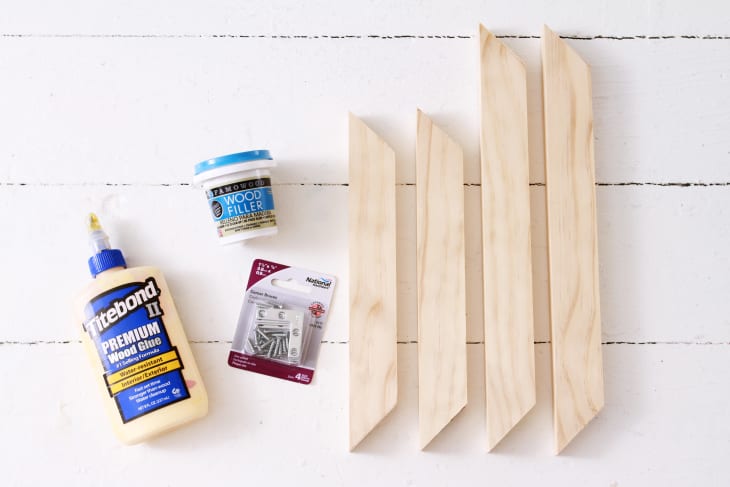 supplies needed to make a DIY picture frame, including brackets, wood, wood glue, and wood filler